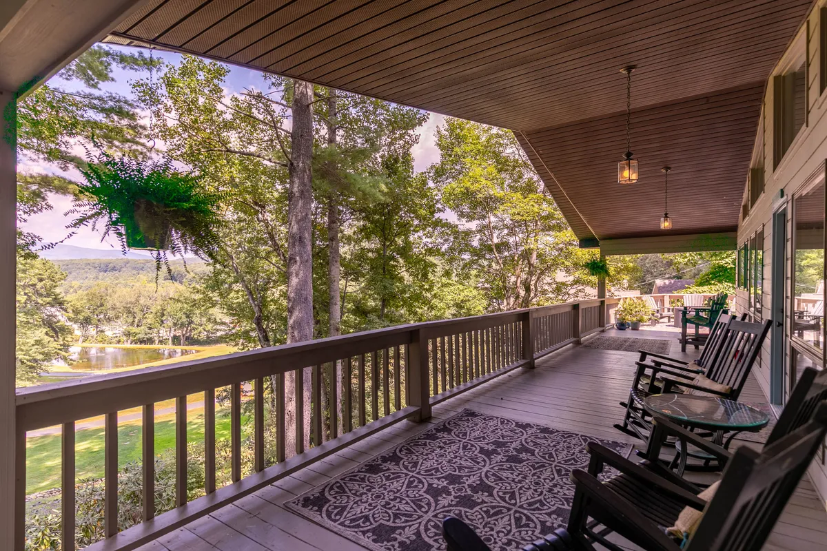This image shows a welcoming porch with classic rocking chairs, a decorative rug, hanging plants, and a view of the distant landscape. The setup is inviting for enjoying peaceful moments, socializing, or simply taking in the surroundings after a day out.