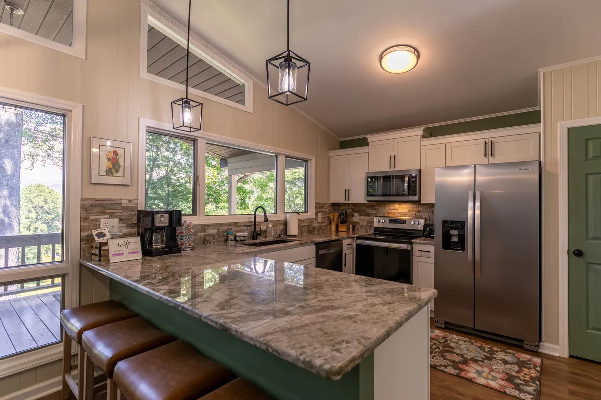 A spacious, modern kitchen with a large island, granite countertops, stainless steel appliances, and wide windows. The kitchen is both functional and inviting, making it ideal for cooking, entertaining, and enjoying the morning sun with coffee.