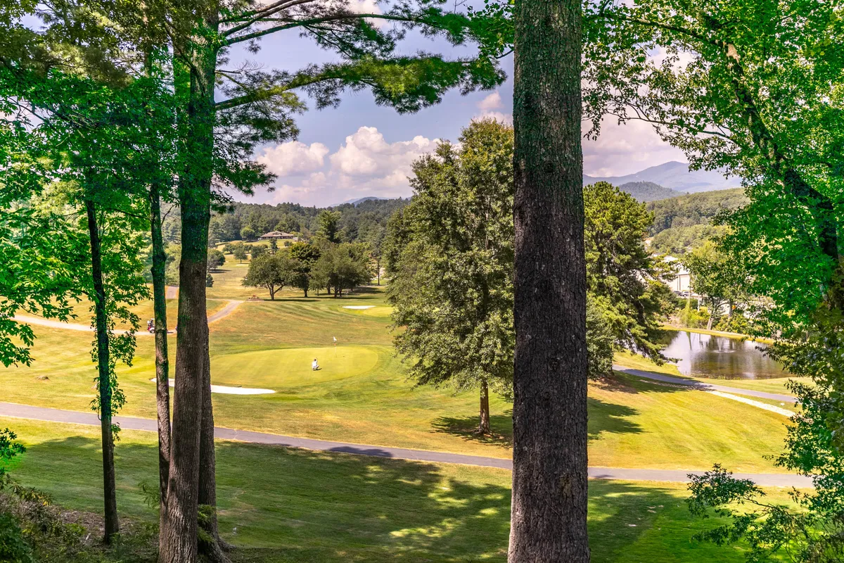 The image reveals sweeping views of the golf course with a water feature, trees, and distant mountains, all bathed in tranquil, golden-hour lighting. The scene is peaceful, inviting viewers to imagine sunsets, nature walks, and the beauty of the fairways just steps away from the property.