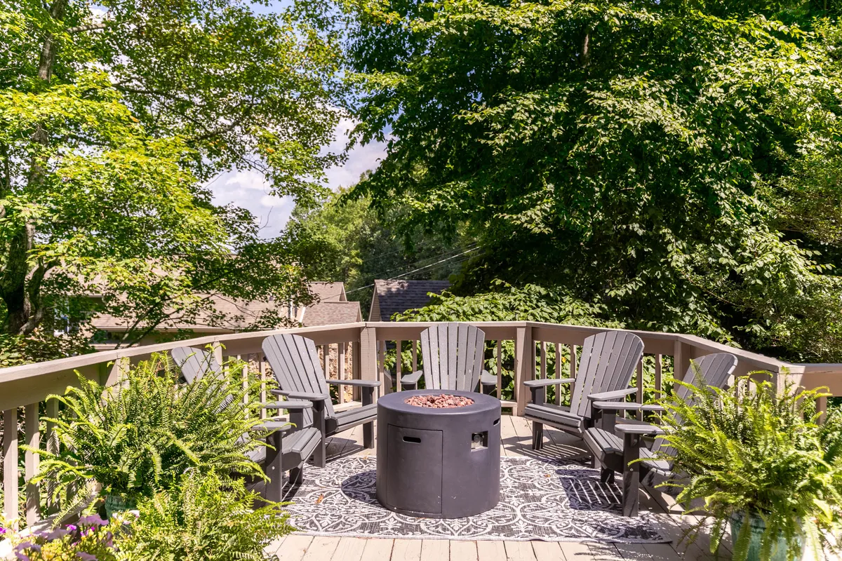 An inviting outdoor area featuring a cozy fire pit surrounded by wooden chairs and lush greenery. The setup is perfect for relaxing after a round of golf, socializing, or simply soaking in the tranquil ambiance as evening falls.