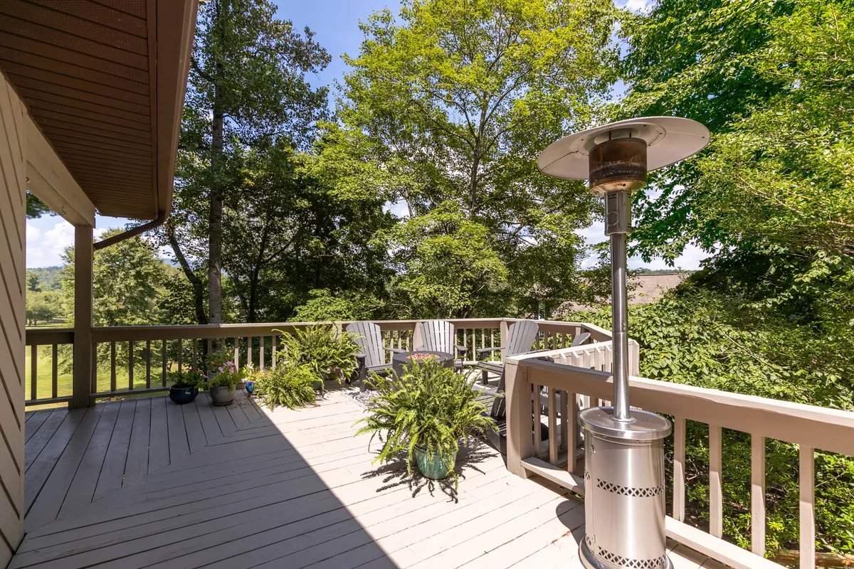 A spacious deck with comfortable seating, potted plants, and lush greenery provides a perfect setting for relaxation after outdoor adventures. The tranquil mood is enhanced by a patio heater, suggesting use throughout the seasons.