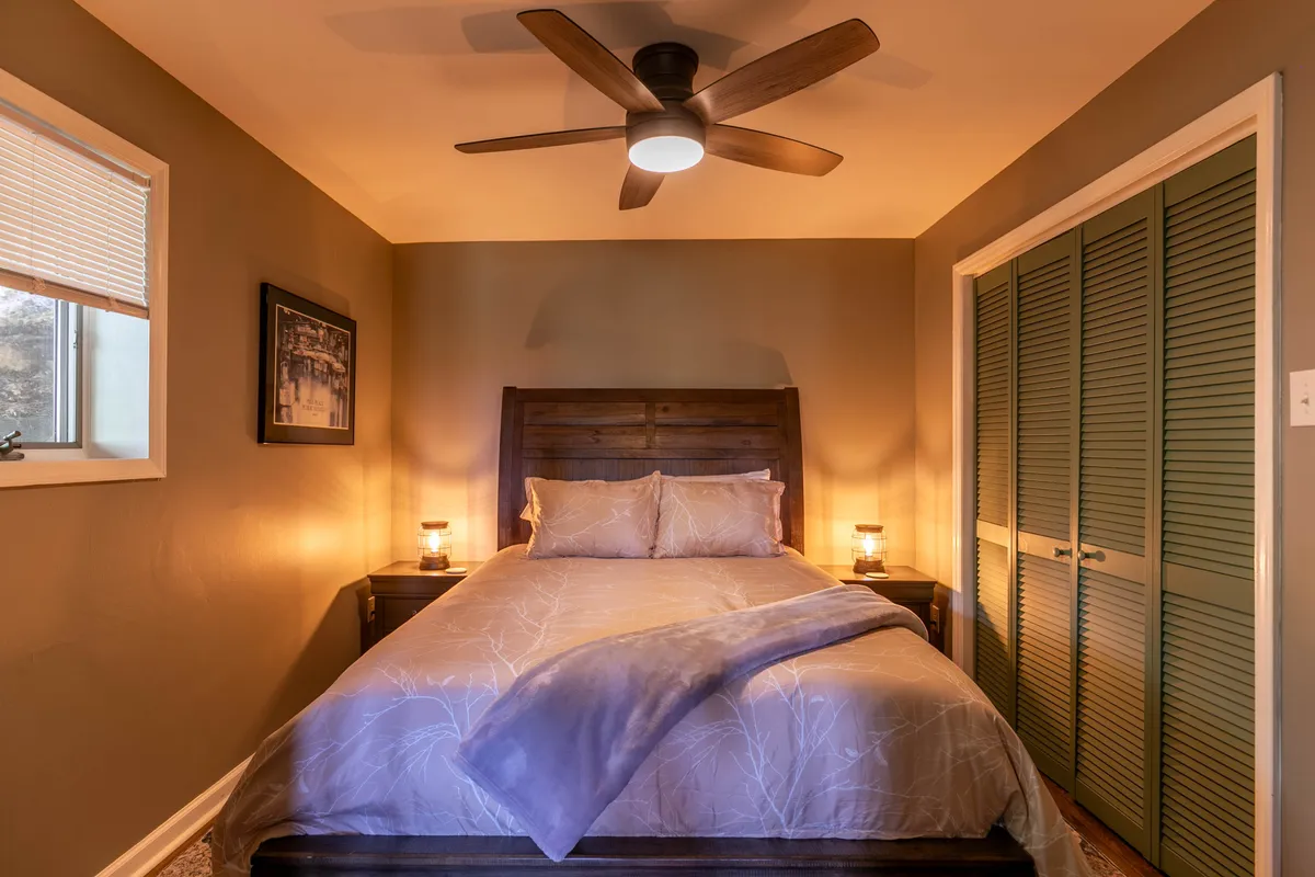 This image features a cozy bedroom with a plush bed, nightstands adorned with lamps, and tasteful artwork above the headboard. The space feels intimate and inviting, ideal for unwinding after a busy day. Soft lighting and gentle decor create the perfect ambiance for restful slumber or quiet late-night reading.